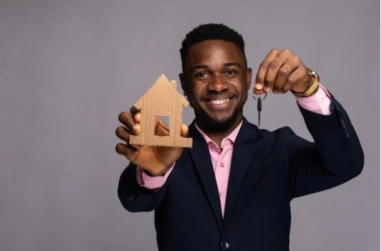 man holding model of a house and keys